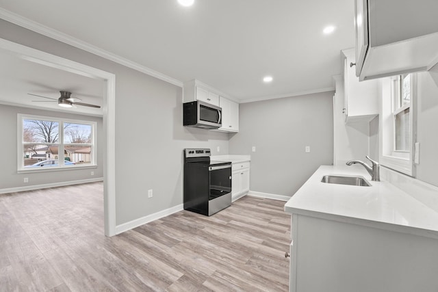 kitchen with white cabinets, appliances with stainless steel finishes, light countertops, and a sink