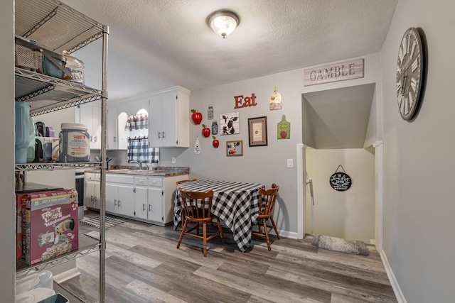 kitchen featuring a textured ceiling, white cabinets, and light wood-type flooring