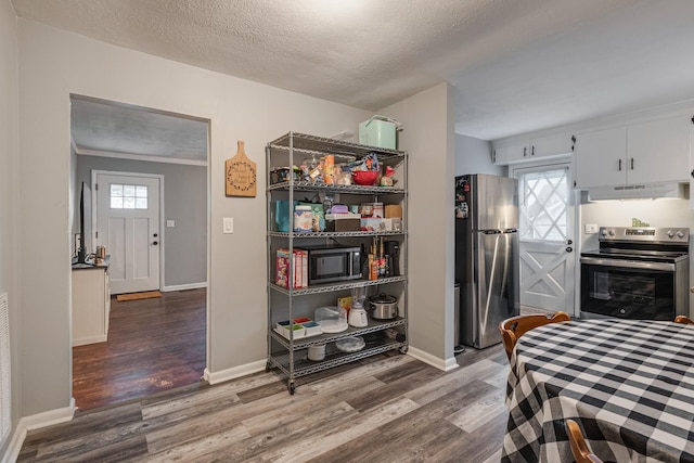 kitchen with hardwood / wood-style flooring, white cabinetry, appliances with stainless steel finishes, and a wealth of natural light