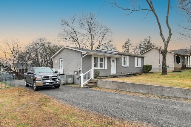 single story home with central AC unit and a lawn