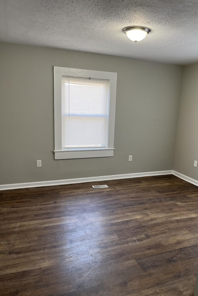 unfurnished room with a textured ceiling and dark hardwood / wood-style flooring