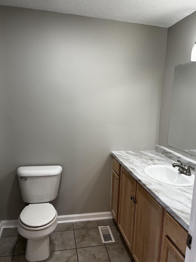 bathroom with tile patterned flooring, vanity, a textured ceiling, and toilet