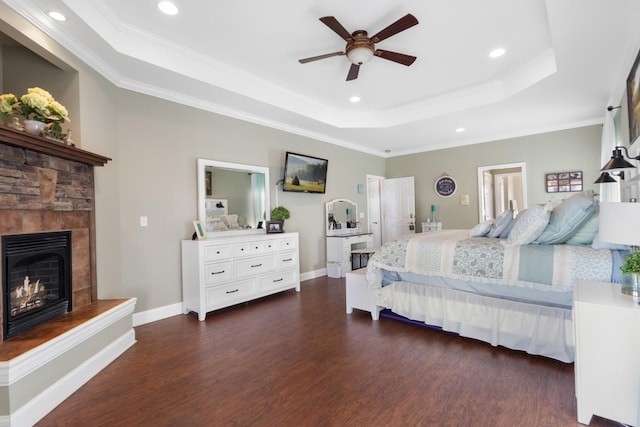 bedroom with crown molding, a tray ceiling, dark wood-type flooring, and ceiling fan