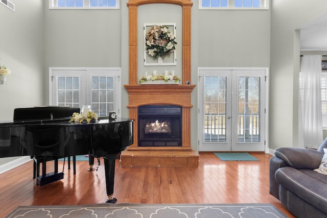 living area with french doors, a high ceiling, and hardwood / wood-style flooring