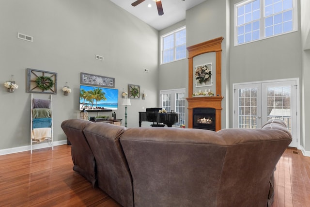 living room featuring french doors, ceiling fan, a high ceiling, and hardwood / wood-style flooring