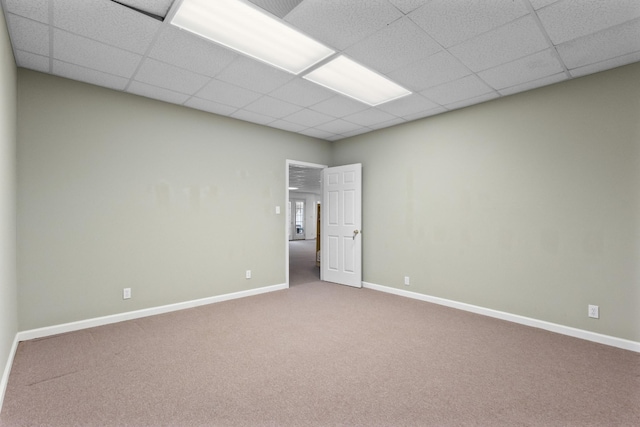 carpeted empty room featuring a drop ceiling