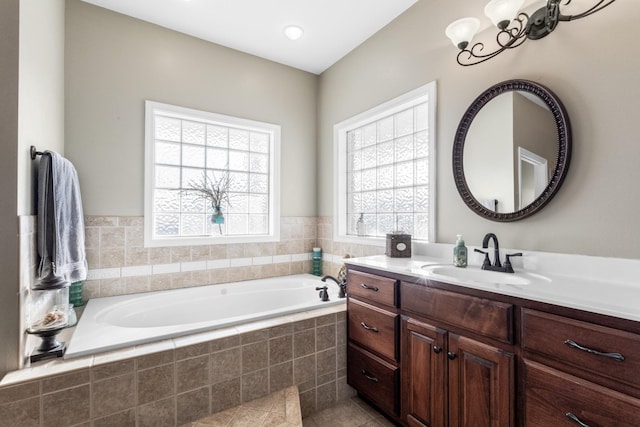 bathroom featuring tiled tub, vanity, and tile patterned flooring