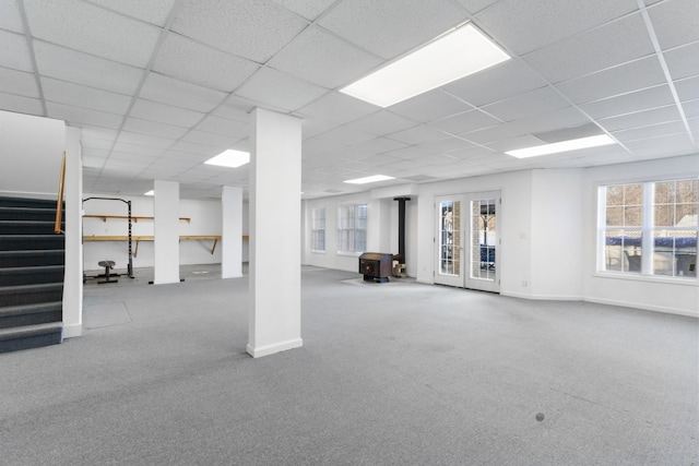 basement with carpet flooring, a drop ceiling, and a wood stove