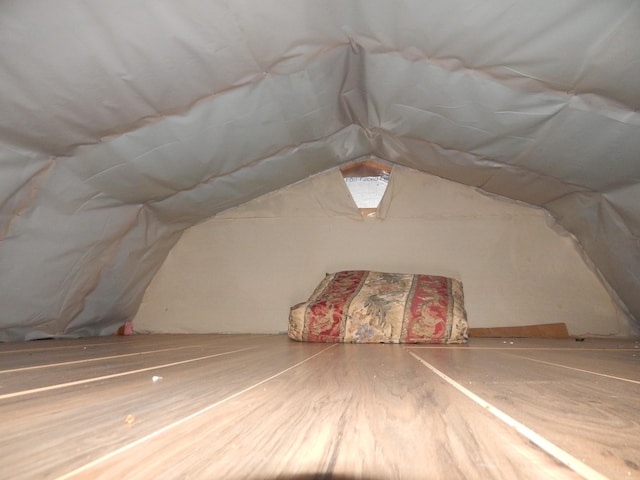 unfinished attic featuring lofted ceiling and hardwood / wood-style floors