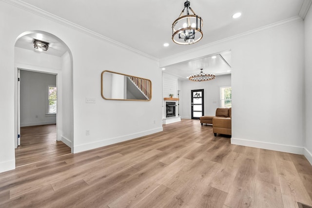 living area with crown molding, a wealth of natural light, and light hardwood / wood-style floors