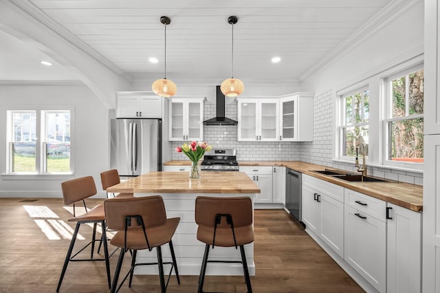 kitchen with wall chimney exhaust hood, butcher block counters, sink, white cabinetry, and appliances with stainless steel finishes