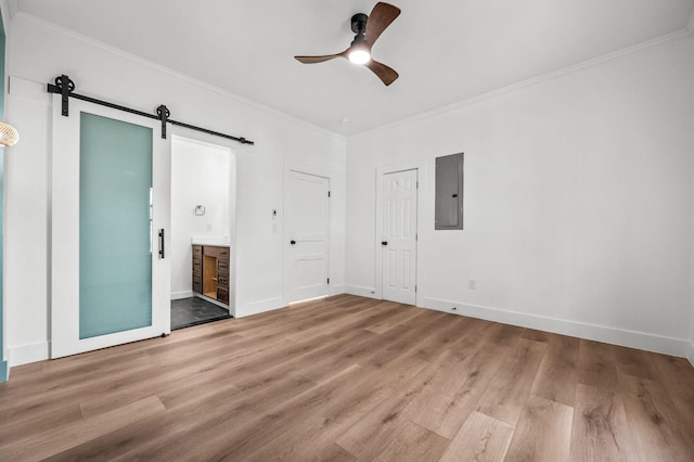 unfurnished bedroom with crown molding, wood-type flooring, electric panel, and a barn door