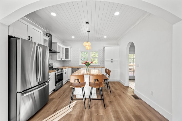 kitchen with stainless steel appliances, a kitchen island, hanging light fixtures, and white cabinets