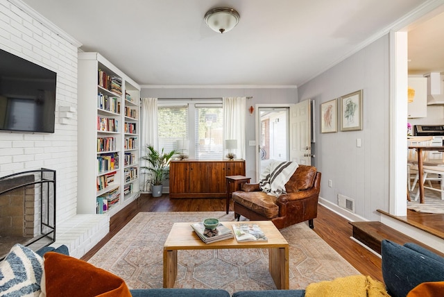 sitting room with hardwood / wood-style flooring, crown molding, and a brick fireplace