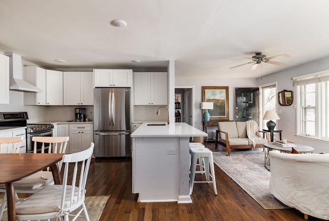 kitchen featuring appliances with stainless steel finishes, wall chimney range hood, and white cabinets