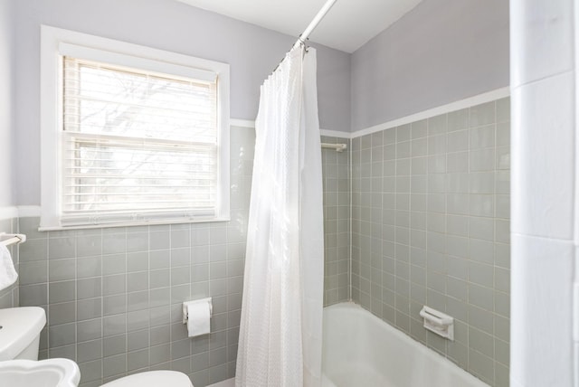 bathroom featuring toilet, shower / bath combo with shower curtain, and tile walls