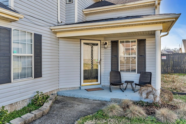 doorway to property with a shingled roof and fence