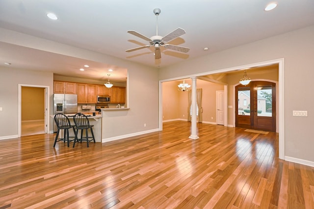 living room with ornate columns, ceiling fan, light wood-type flooring, and french doors