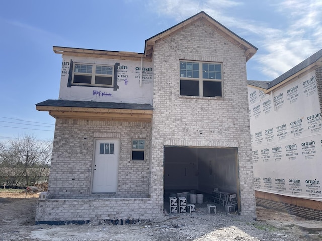 unfinished property with an attached garage and brick siding