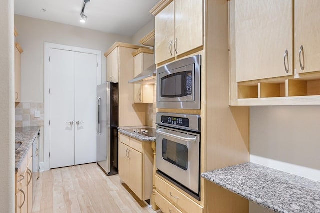 kitchen with light brown cabinetry, light stone countertops, light hardwood / wood-style flooring, and stainless steel appliances