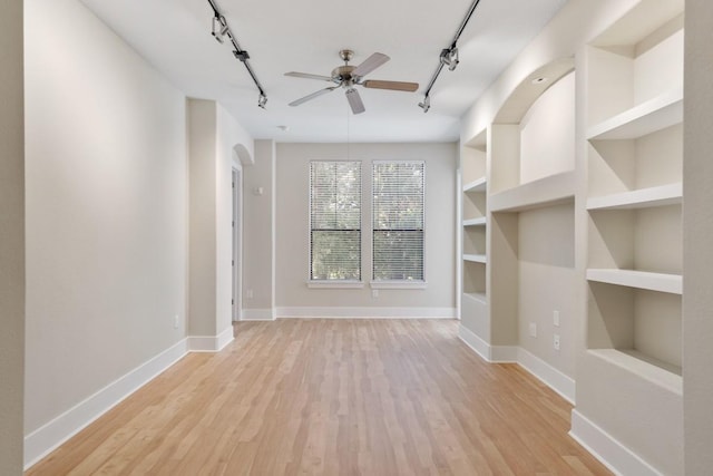 unfurnished living room featuring track lighting, built in features, and light hardwood / wood-style flooring