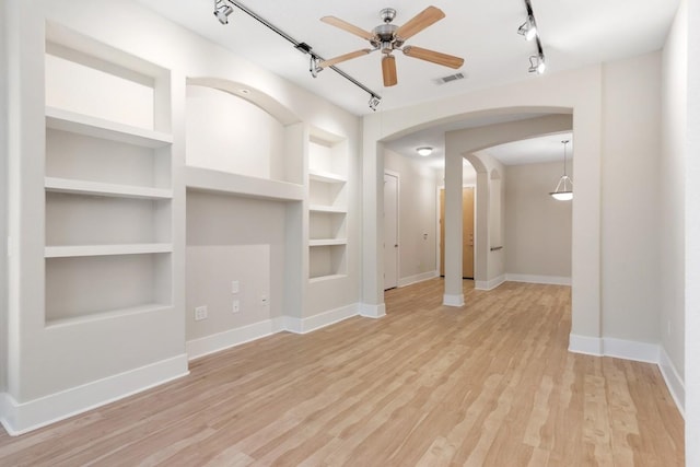 unfurnished living room featuring ceiling fan, rail lighting, built in features, and light wood-type flooring