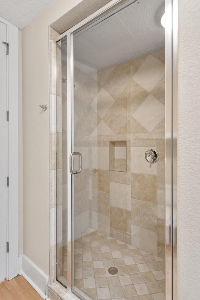 bathroom featuring wood-type flooring, an enclosed shower, and a textured ceiling