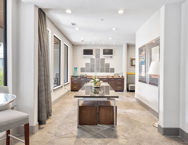 kitchen featuring dark brown cabinetry, a breakfast bar area, a textured ceiling, and a kitchen island