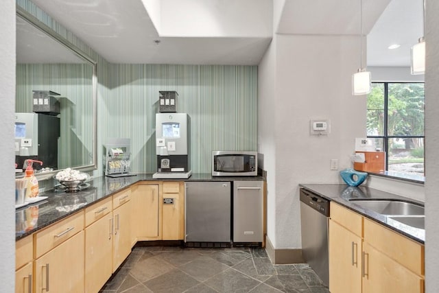 kitchen featuring sink, hanging light fixtures, dark stone counters, light brown cabinets, and stainless steel appliances