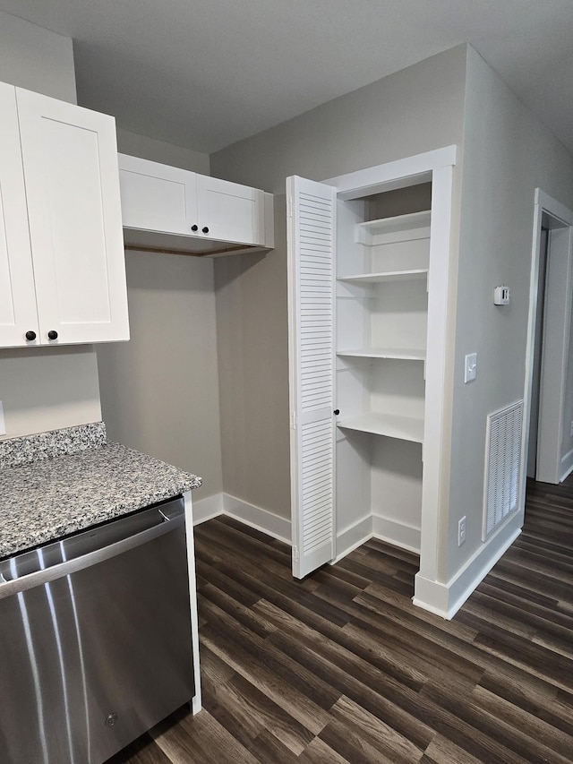 kitchen with white cabinetry, light stone countertops, dark wood-type flooring, and stainless steel dishwasher