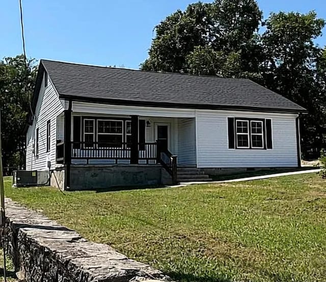 view of front of home featuring cooling unit, a front yard, and covered porch