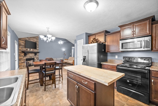 kitchen featuring a kitchen island, a fireplace, wood counters, sink, and stainless steel appliances