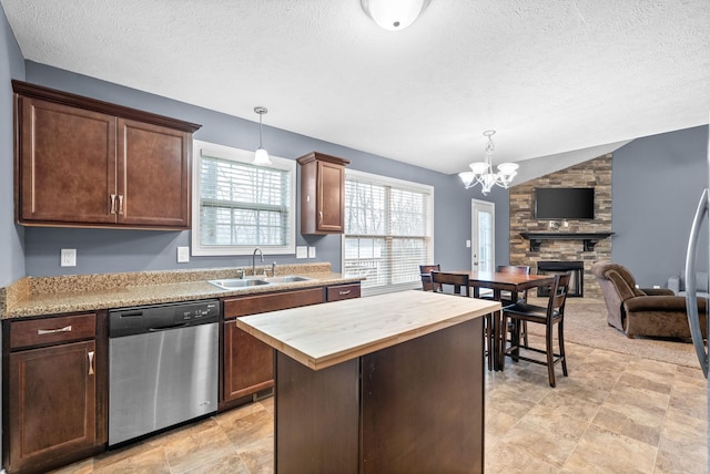 kitchen featuring lofted ceiling, sink, dishwasher, a kitchen island, and decorative light fixtures