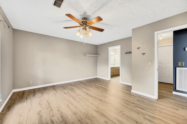 empty room with ceiling fan, a textured ceiling, and light hardwood / wood-style floors