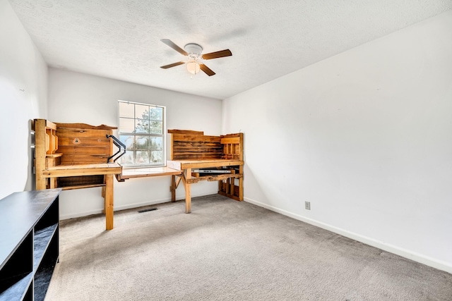 misc room featuring ceiling fan, light colored carpet, and a textured ceiling