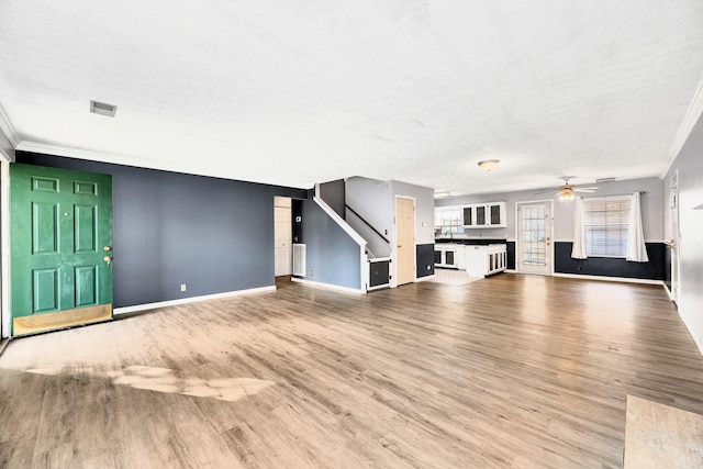 unfurnished living room featuring hardwood / wood-style flooring, ornamental molding, a textured ceiling, and ceiling fan