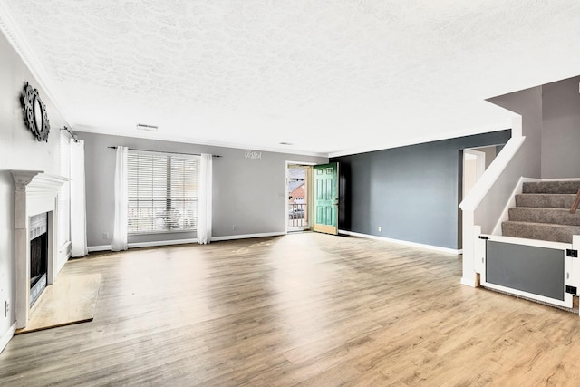 unfurnished living room featuring crown molding, a high end fireplace, light hardwood / wood-style floors, and a textured ceiling