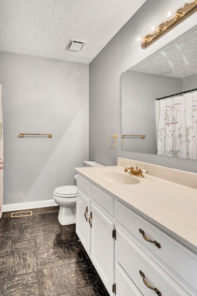 bathroom featuring vanity, a textured ceiling, and toilet