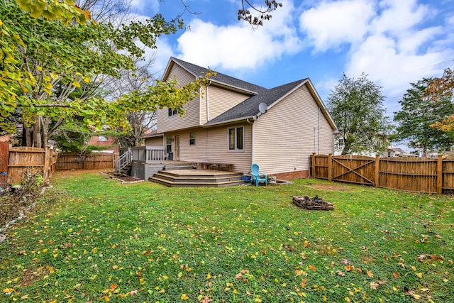 rear view of property with a wooden deck, a yard, and a fire pit