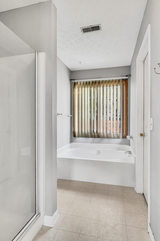 bathroom with tile patterned floors, a textured ceiling, and separate shower and tub