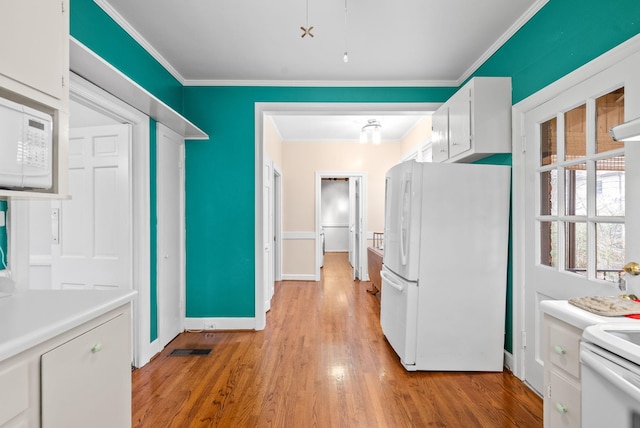 kitchen featuring crown molding, white appliances, white cabinets, and light wood-type flooring