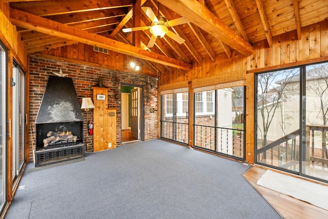 unfurnished living room with carpet floors, vaulted ceiling with beams, a wealth of natural light, and ceiling fan