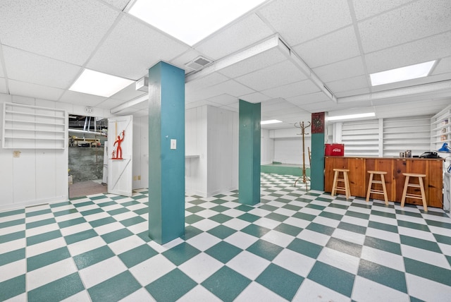 basement featuring bar and a paneled ceiling