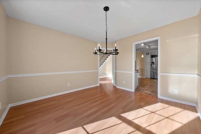 unfurnished dining area featuring a notable chandelier and wood-type flooring