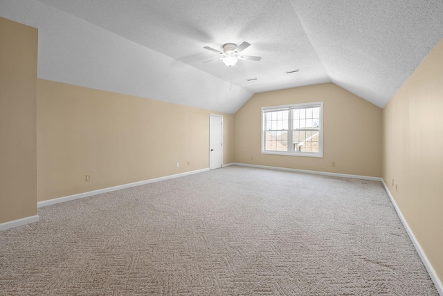 bonus room featuring ceiling fan, lofted ceiling, light colored carpet, and a textured ceiling