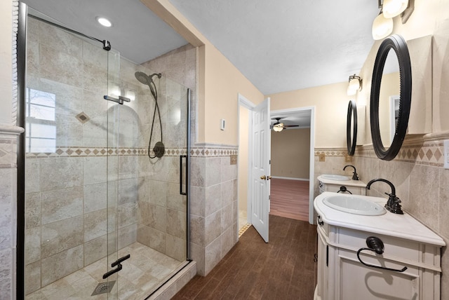 bathroom with hardwood / wood-style flooring, vanity, a shower with shower door, and tile walls