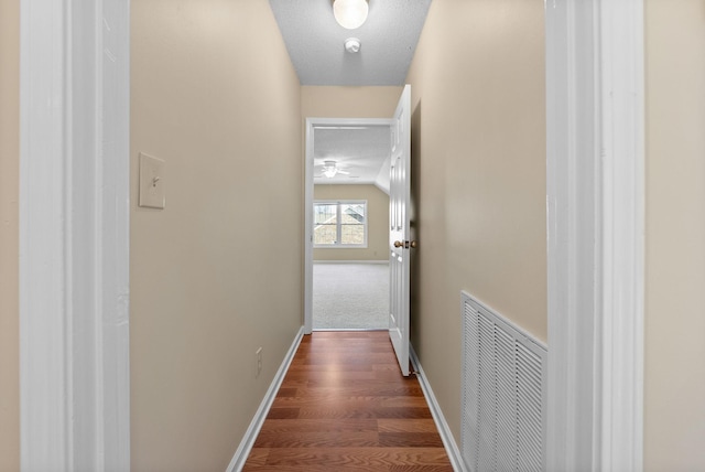 hall with lofted ceiling, dark hardwood / wood-style flooring, and a textured ceiling