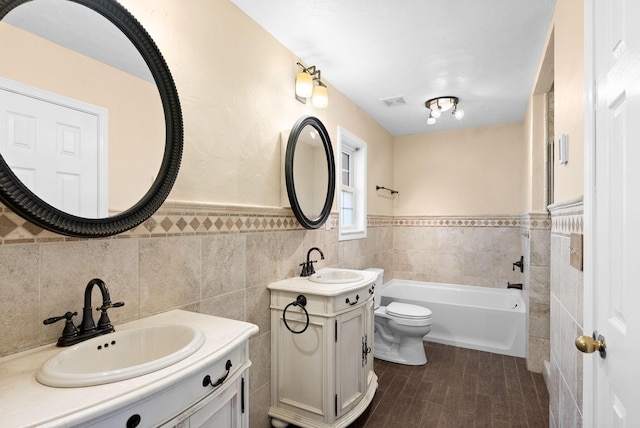 bathroom featuring vanity, tile walls, a tub, and toilet