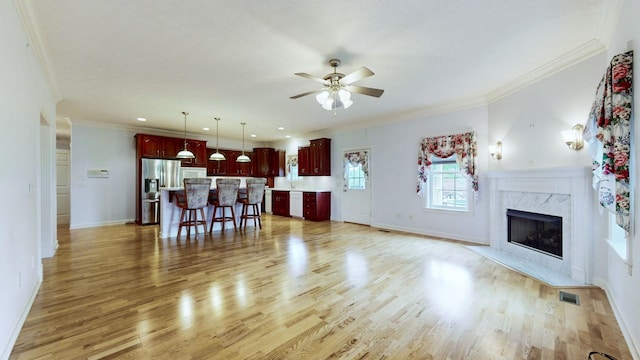 living room featuring ornamental molding, ceiling fan, light wood-style floors, and visible vents