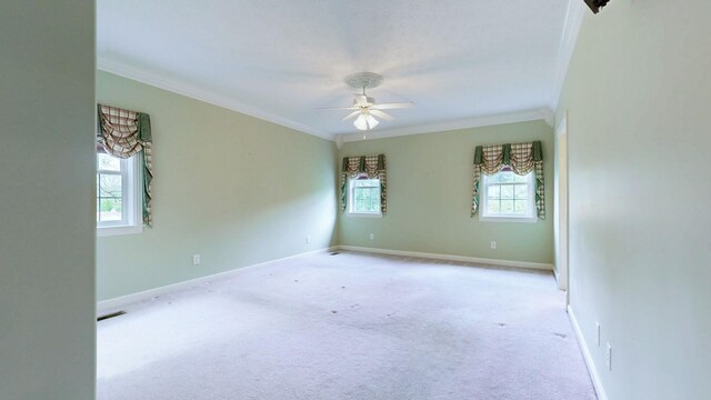empty room featuring ornamental molding, a ceiling fan, light carpet, and baseboards